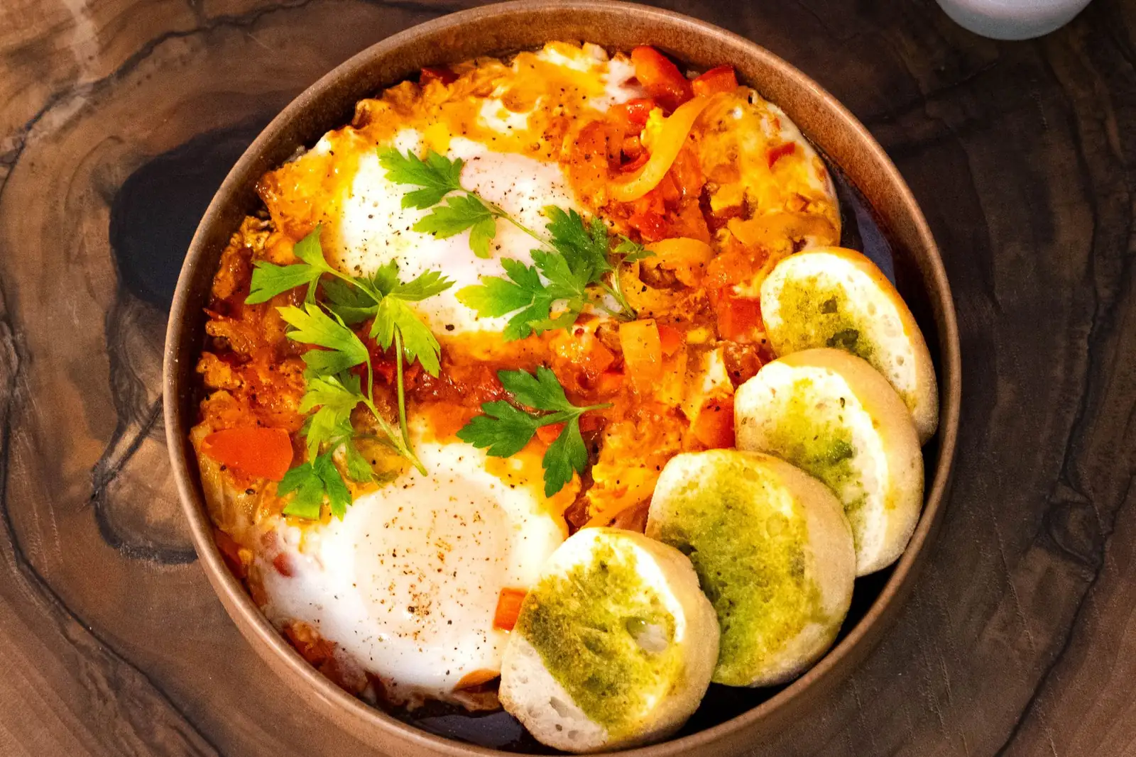 Une shakshuka : œufs pochés dans une sauce tomate, avec du pain grillé